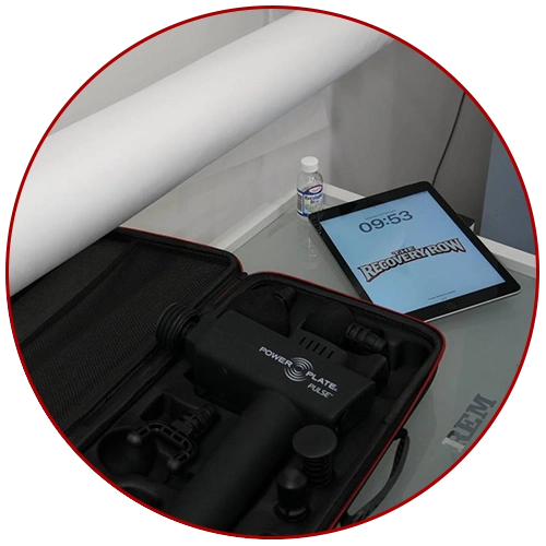 massage gun smart tablet and eucalyptus oil on clean glass table with a medical couch roll dispenser above inside the recovery row clinic in nottingham