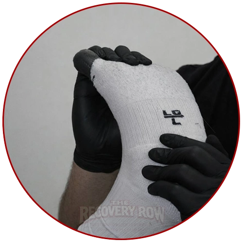 sports massage therapist wearing latex gloves manipulating a clients foot